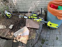 Full view of the Ryobi string trimmer laid out showing the shaft, handle, and battery pack attached