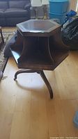 Full view of the antique hexagonal side table with visible six individual shelf sections and castor wheels on legs.