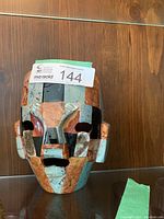 Front view showing mosaic ceramic tiles in blue, terracotta, black and beige making facial features and overall mask shape