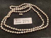 Long freshwater pearl necklace laid out flat with auction lot number