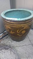 Large ceramic garden planter with gold Oriental dragon artwork on brown exterior and turquoise glazed interior, photographed straight on front.