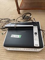 Top view of Sony S-Master 5-disc amplifier system with remote and cords placed on top, showing front panel controls and center speaker.