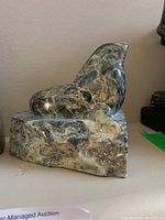 Side view of marbled stone sea lion sculpture showing polished finish and form