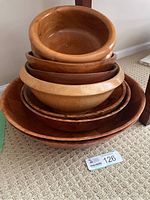 Stacked view of all eight bowls showing varied sizes and wood tones.