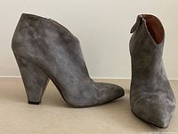 Left side and front view of single grey suede ankle boot showing conical heel and pointed toe