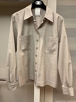 Front view of beige wool long-sleeve shirt with two patch pockets and mother-of-pearl CC logo buttons