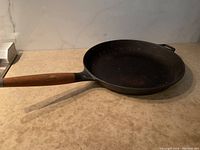 Single Copco cast iron frying pan on counter showing side profile and wood handle length.