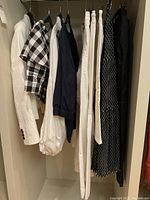 Overview of seven women's black, white and navy garments hanging on a rack