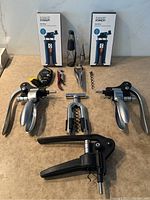 Full view of entire lot with two boxed corkscrews, multiple corkscrews, wine stopper, and aerator displayed on countertop.