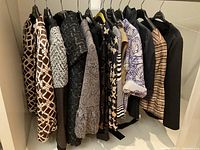 Rack view showing nine assorted jackets and tops on hangers