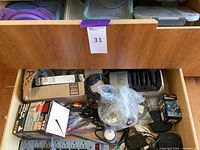 Drawer with assorted cords, extension cords, miniature Bose USB speakers, boxed items, and small appliances.