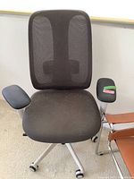 Front view of black fabric mesh office chair with padded armrests and wheeled base
