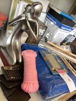 Photo showing silver-toned abstract figurine, scientific calculator, Palm Pilot, pink cloth roll, and background coin counter box.
