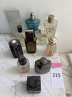 Overview of nine designer men's fragrance bottles on a marble surface, showing variation in size, brand, and usage.