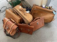 Six leather luggage pieces displayed on tiled floor