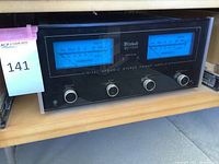 Full front view of McIntosh MC7300 amplifier showing illuminated blue watt meters and control knobs with rack rails