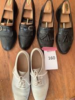 Front view of three pairs of men's shoes showing Bally and J and M loafers and Cole Haan white bucks
