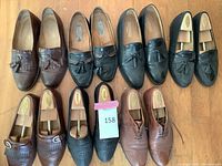 Seven pairs of men's dress shoes arranged side by side on wooden floor