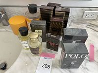 All fragrance bottles and boxes on marble counter: two Acqua di Parma bottles with yellow packaging, multiple Eau de Toilette tester and retail boxes, including Costume National, Polo Black and Quorum