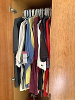 Photo of 11 men's golfing shirts hanging on hangers in a closet, showing different colors and styles.