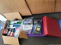 Full view of all items including label maker, organizer, stapler, tape, binders, and folders arranged on floor.