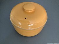 Yellow ceramic casserole dish with lid viewed from the top, showing vent hole on the lid.