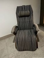 Front view of electric lounge chair showing cushioned headrest pillow and patterned fabric upholstery with vertical wavy stripes.