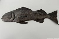 Full view of metal fish sculpture showing scale and fin details