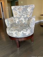 Full view of swing chair showing floral upholstery and wooden legs.