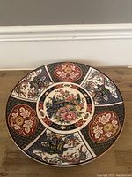 Top view of the round ceramic charger plate showing detailed peacock and floral designs in the center and patterned rim sections.