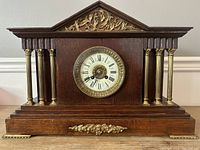 Full front view of wooden mantel clock with brass columns and floral appliques