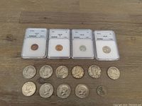 Full view of 15 American coins including four slabbed certified coins and loose coins on wooden surface