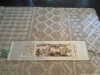 Full view of entire scroll tapestry on floor showing brocade borders and central embroidered scene