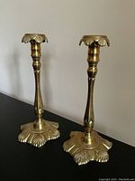Pair of tall brass candlesticks showing height and leaf-patterned wide bases