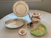 Full lot of bone china items displayed on a white table, including tea pot, serving plates, and decorative dishes