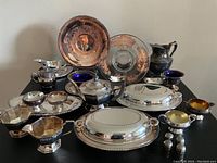 Full lot of various silver plated serving pieces and accessories on black table