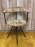 Front view of chair showing circular rattan seat and curved rattan backrest on black metal legs
