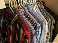 Collection of men’s plaid and patterned cotton casual shirts on hangers, various colors and patterns including red, blue, green, and brown.
