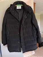 Full front view of black Danier winter coat hanging on wooden hanger