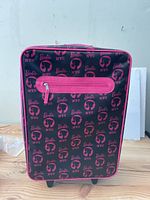Front view of the Barbie suitcase showing the black and pink NYC themed print and front zippered pocket.