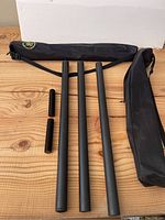 Two unassembled black segment Kung Fu staffs with two short connector pieces each, and two black carrying bags with straps.