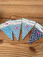 Four Celebrate It brand party banners laid out showing polka dot patterns on triangular flags in various shades of blue.