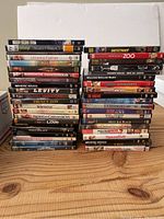 Photo showing stacked DVD movie titles visible on spines, including Deep Blue Sea, Bangkok Dangerous, Mystic River, Serendipity, etc.