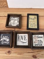 Top view of all five wooden frames arranged on wooden surface showing all sayings.