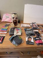 Full overview of Halloween makeup mask and assorted accessories, all new and packaged on a wooden table.