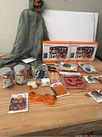 Full display of Halloween item assortment on table with hanging ghost figure and boxed light sets visible in background.