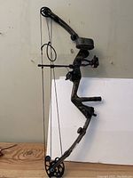 Full side view of the camo-patterned Light Vibra Flex compound bow showing bowstring, cams, grip, sight, and stabilizer.