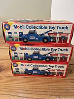 Front view of three boxed Mobil Collectible Toy Trucks stacked on top of each other showing colorful packaging and truck illustration