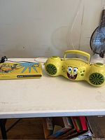 Photo showing SpongeBob SquarePants themed yellow radio/CD player and yellow DVD player side by side on a white table.