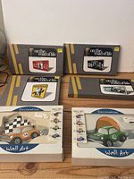 Four rectangular photo frames with license plate themes and two decorative vintage car wall art boxes on wooden surface.
